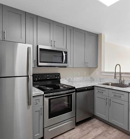 a kitchen with gray cabinets and stainless steel appliances at Excalibur Apartment Homes, Bellevue, WA, 98004
