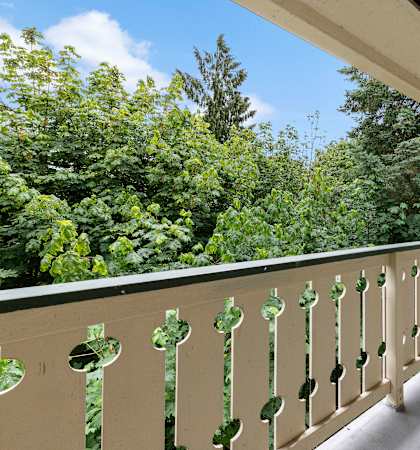 a balcony with a door and trees in the background at Swiss Gables Apartment Homes, Kent, 98032