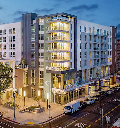 A modern apartment building with cars parked in front.