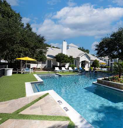 A large swimming pool with a small waterfall and a hot tub.