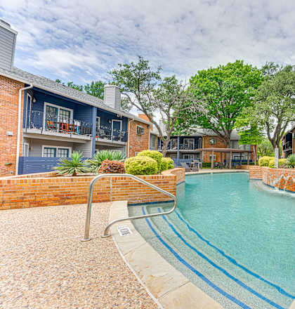 A small pool surrounded by a brick wall and steps leading to a house.
