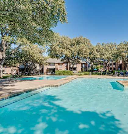 A swimming pool surrounded by trees and houses.