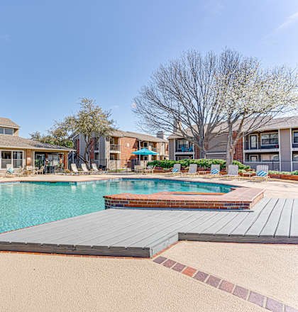 A large swimming pool in front of a building with a red brick exterior.