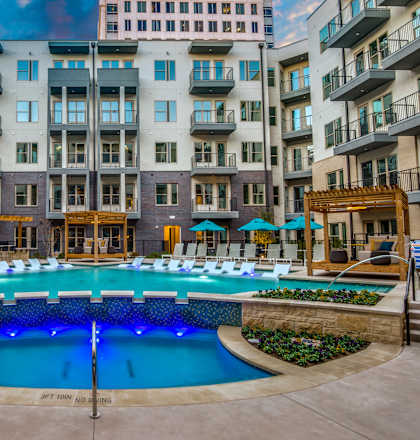 A large swimming pool surrounded by a stone wall and lounge chairs.