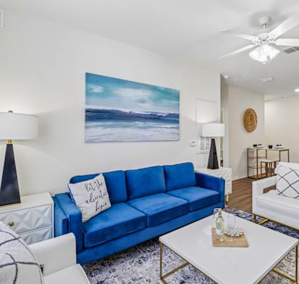A living room with a blue couch and a white coffee table.