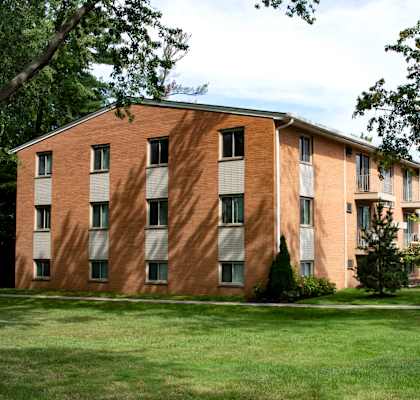 A large brick building with a green lawn in front.