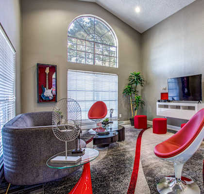 A living room with a grey couch, red chairs and a television.