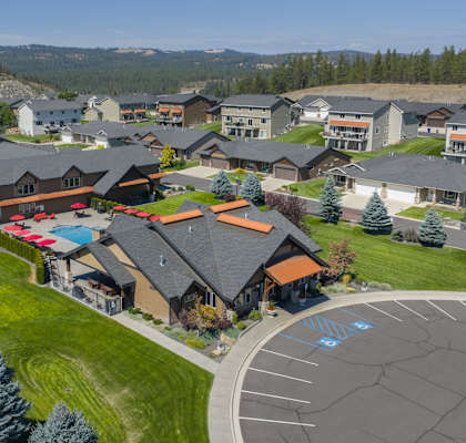 A large building with a red roof is surrounded by a parking lot.