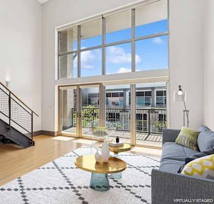 A living room with a staircase and a large window.
