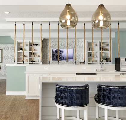 A kitchen with a white counter and blue chairs.