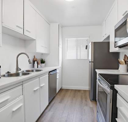 A modern kitchen with white cabinets and stainless steel appliances.