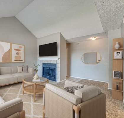 A living room with a fireplace and a TV on the wall.