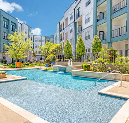 A swimming pool in a residential area surrounded by trees and buildings.