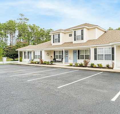 A two-story house with a parking lot in front.