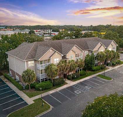 A sunset view of a residential area with apartment buildings and a parking lot.