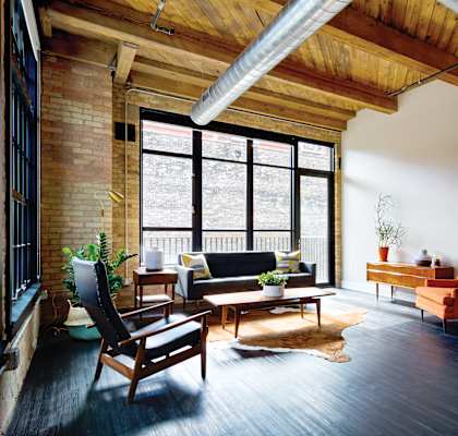 A living room with a black couch and a wooden chair.