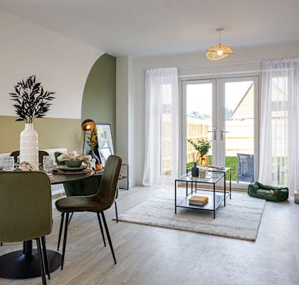 A dining room with a table set for four and a view of the backyard.