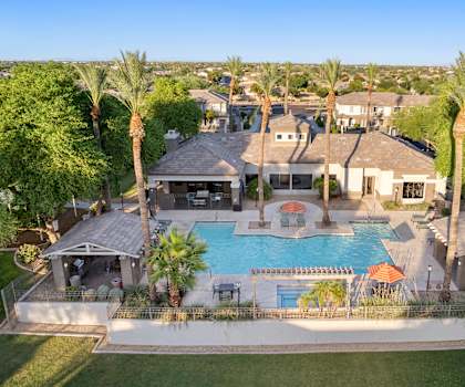 A large house with a pool surrounded by palm trees.
