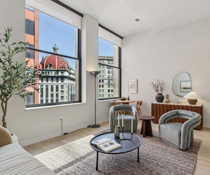A living room with a large window and a view of a building with a red roof.