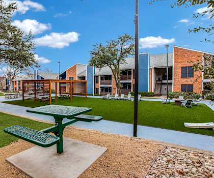 A green picnic table is in the middle of a grassy area.