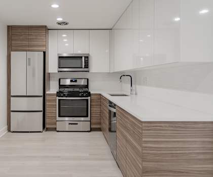 A modern kitchen with a refrigerator, microwave, oven, and sink.