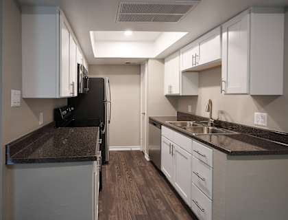 a kitchen with white cabinets and black countertops