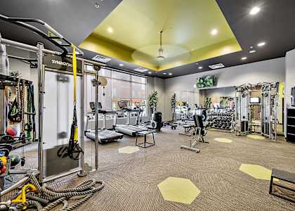 A gym with a variety of equipment including a squat rack, bench, and weights.