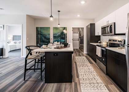 A modern kitchen with dark wood floors and a large island.