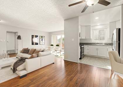 A modern living room with a white couch and a kitchen in the background.