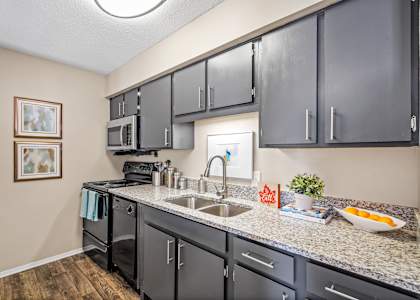 a kitchen with granite counter tops and dark cabinets at 701 South Apartments in Mobile, AL