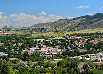 A cityscape with buildings and greenery under a blue sky with clouds.