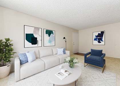A living room with a white couch, a blue chair, and three framed pictures on the wall.
