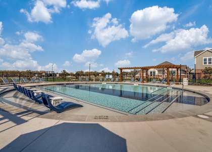 A large outdoor swimming pool with a slide and a gazebo in the background.