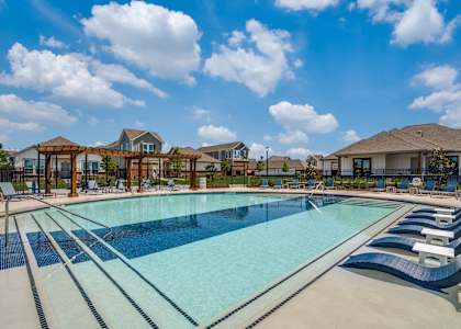 A large outdoor swimming pool with loungers and a clear blue sky.