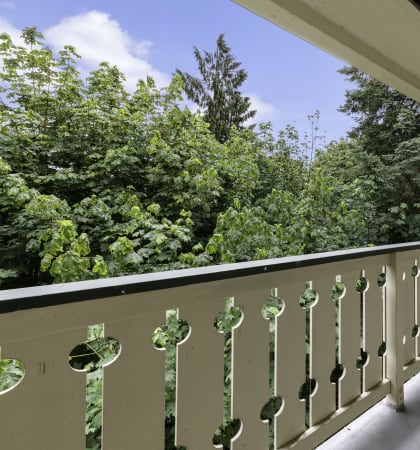 a balcony with a door and trees in the background