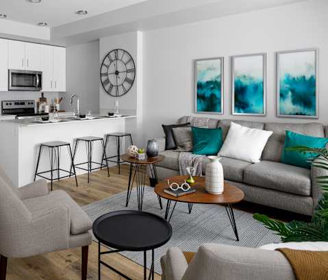 a living room with a kitchen in the background and a couch and chairs in the foreground