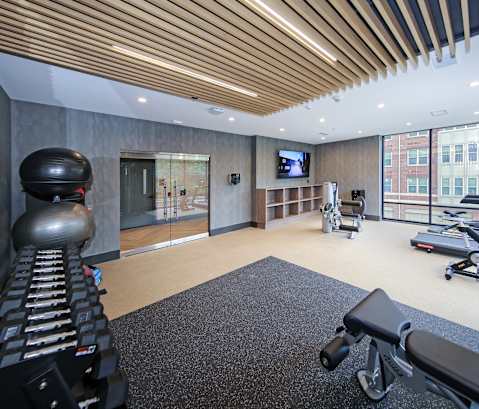 A gym with a variety of equipment including a treadmill, weights, and a television.