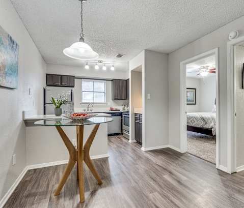 A modern kitchen with a glass table and a wooden X base.