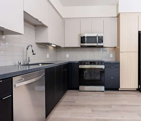 A kitchen with black and white appliances and wooden cabinets.