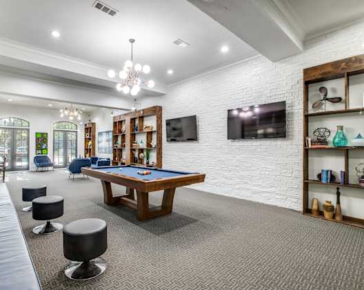 A room with a pool table and a television mounted on the wall.
