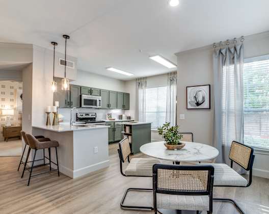 A kitchen with a table and chairs in front of a window.