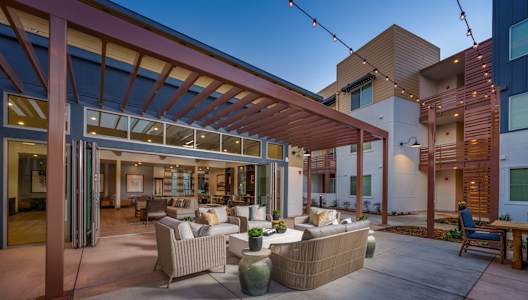 a patio with couches and chairs in front of a building
