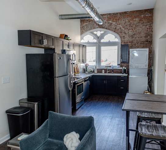 an open kitchen with stainless steel appliances and a wooden table and chairs at University Commons in Pittsburgh, PA