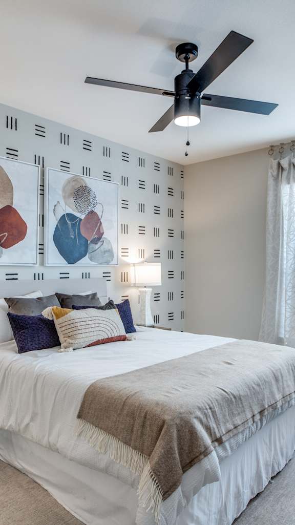A bedroom with a bed, nightstand, and a ceiling fan.