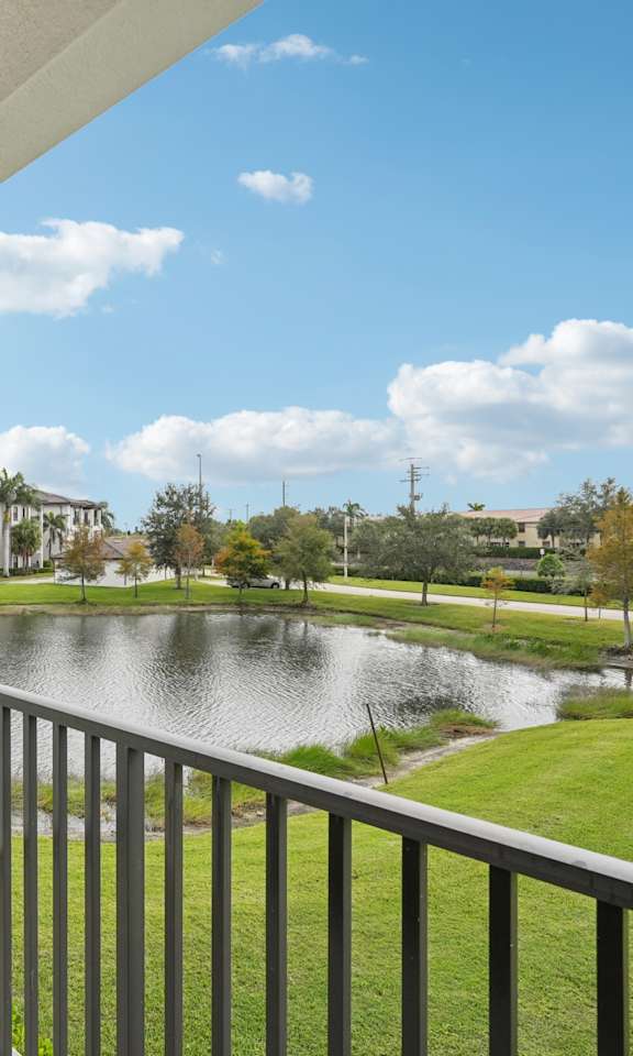 A balcony overlooks a pond and a park.