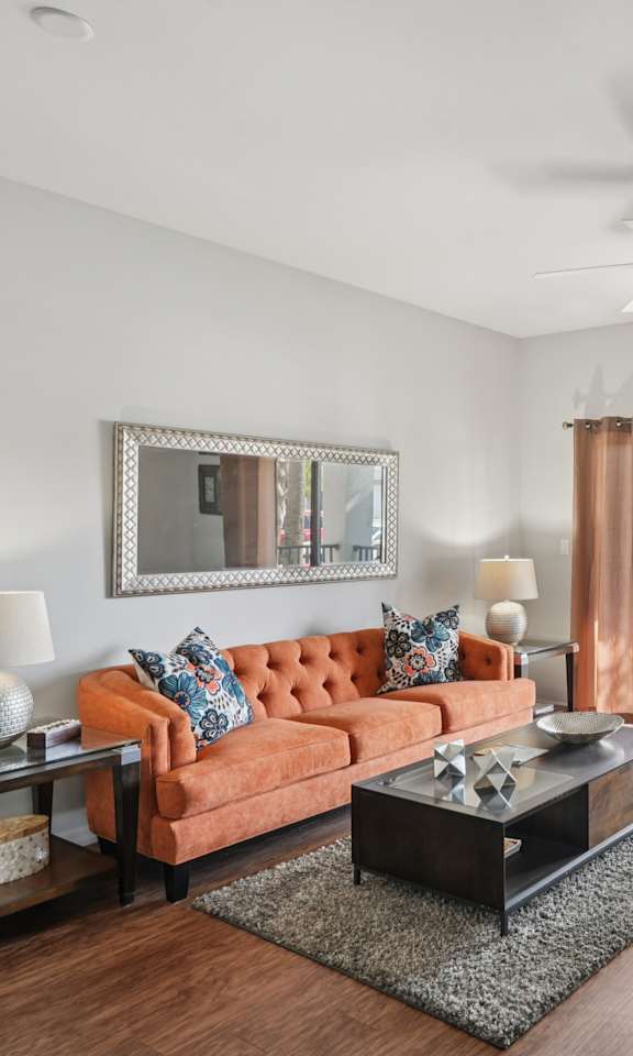 A living room with a brown sofa, a coffee table, and a ceiling fan.