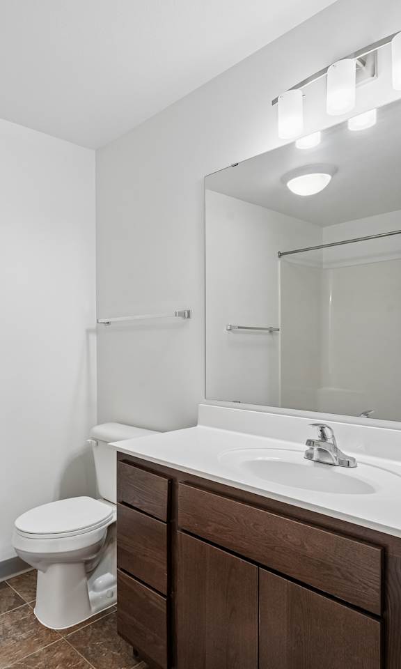 A white bathroom with a toilet, sink, and mirror.