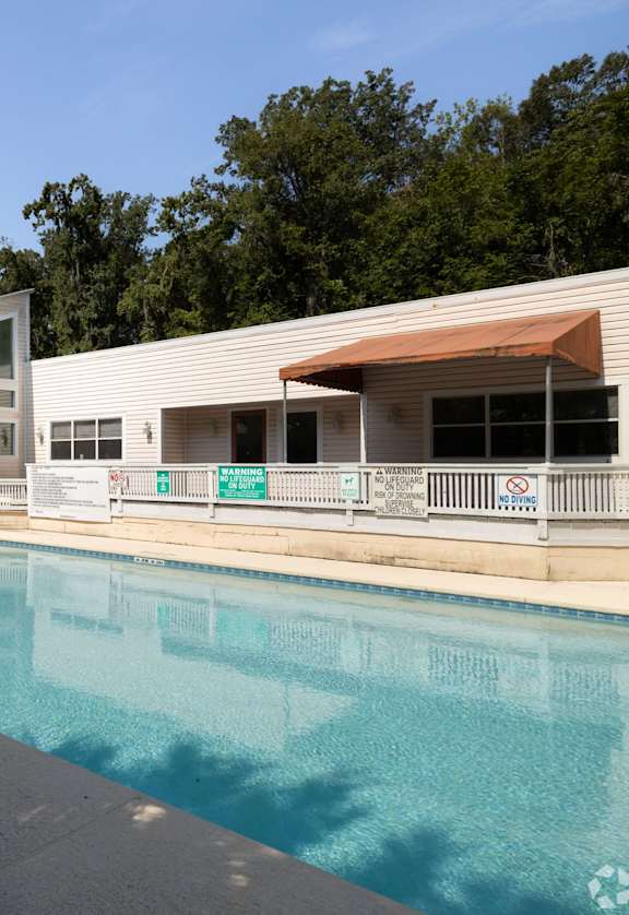a swimming pool in front of a white house with a palm tree