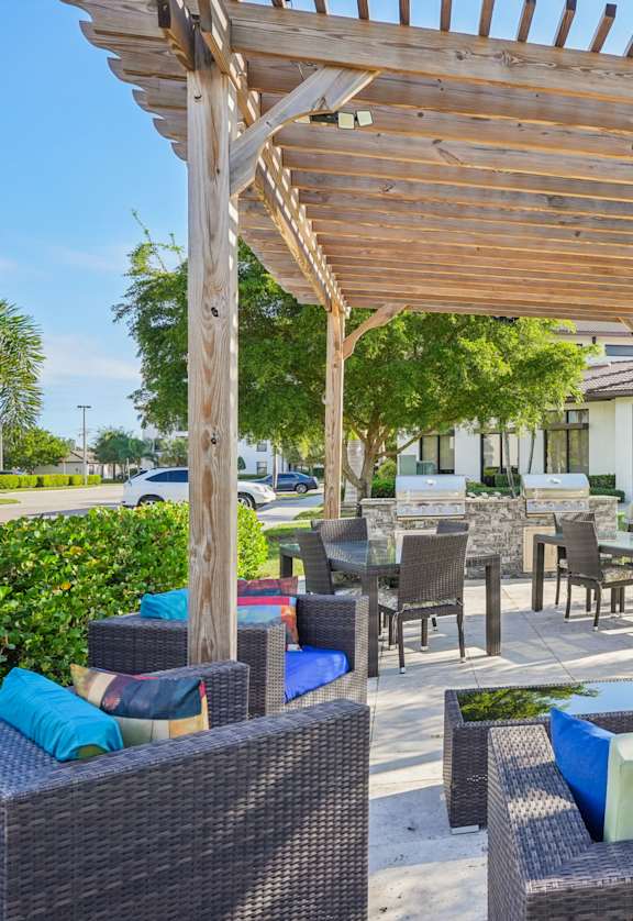 A wooden pergola over a patio with wicker furniture.
