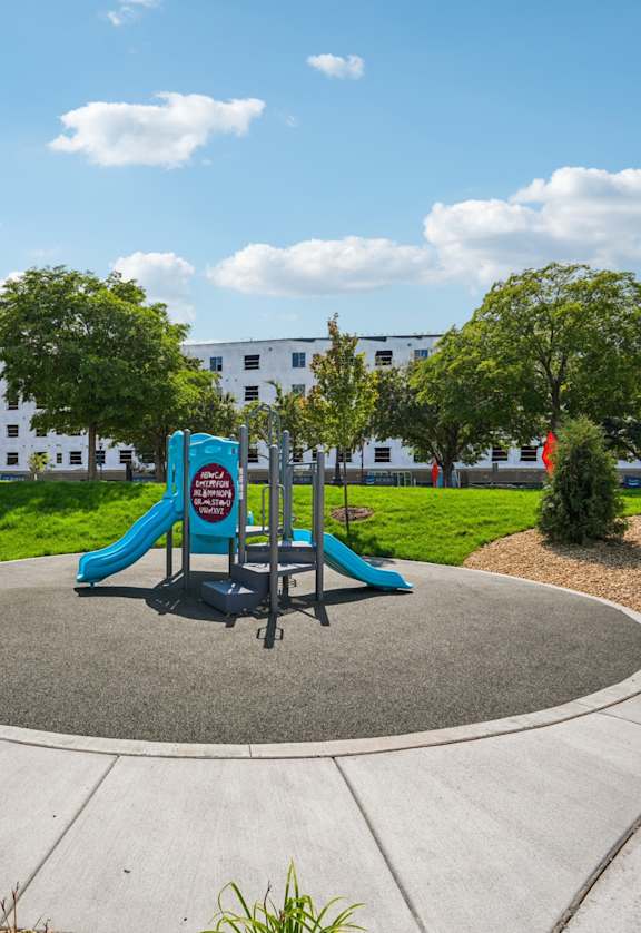A playground with a slide and a bench in the foreground.